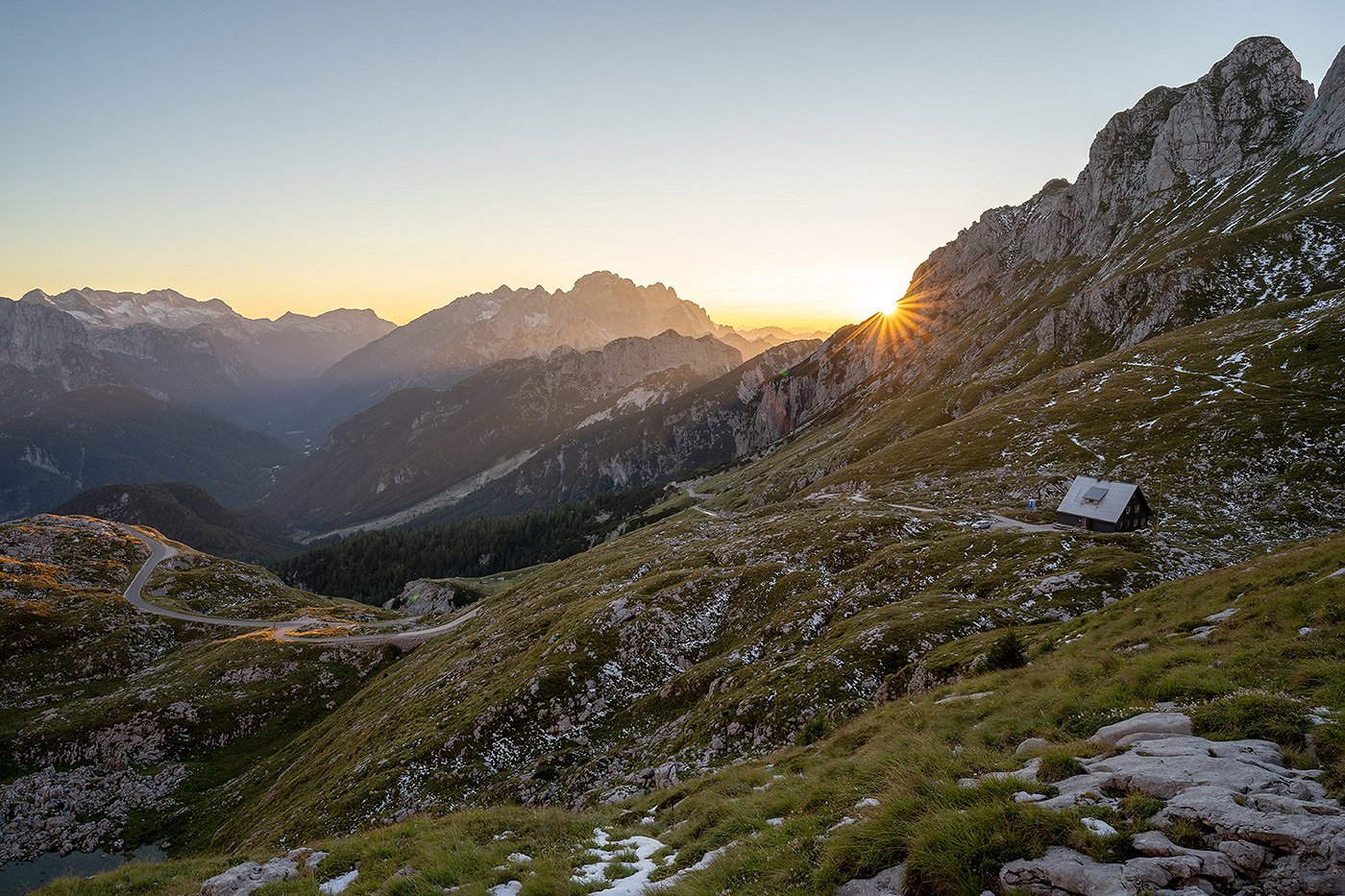 Die Sonne geht hinter den Bergen rund um die Mangarthütte unter