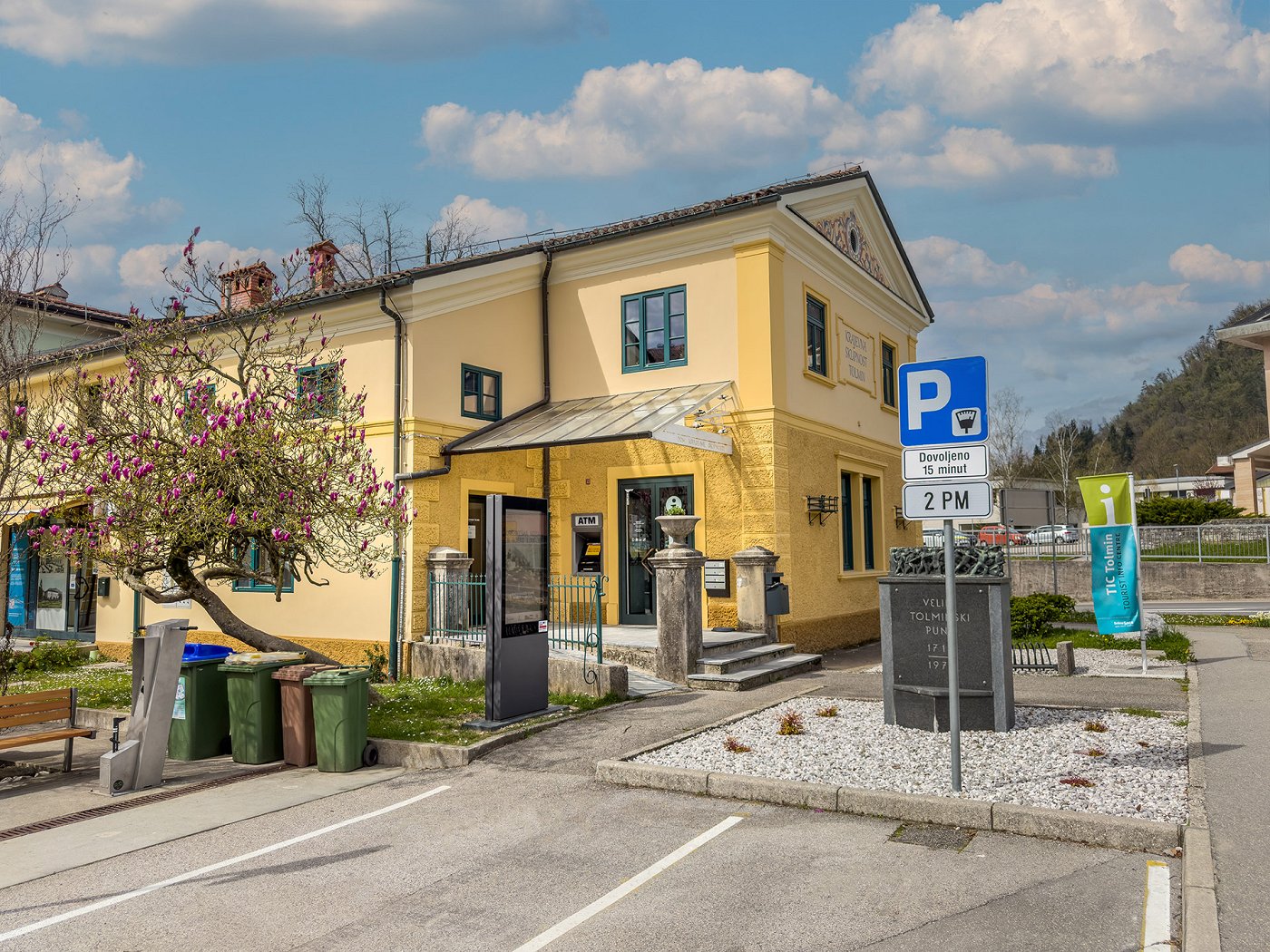 the building of the Tolmin Tourist Information Centre in the centre of Tolmin, in front of which is a parking lot for 15 min